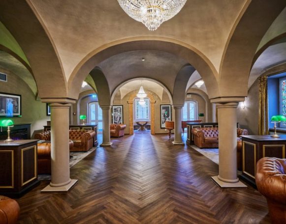 Elegante Lobby mit Holzboden, gewölbten Decken und Leder-Sofas in warmem Licht.